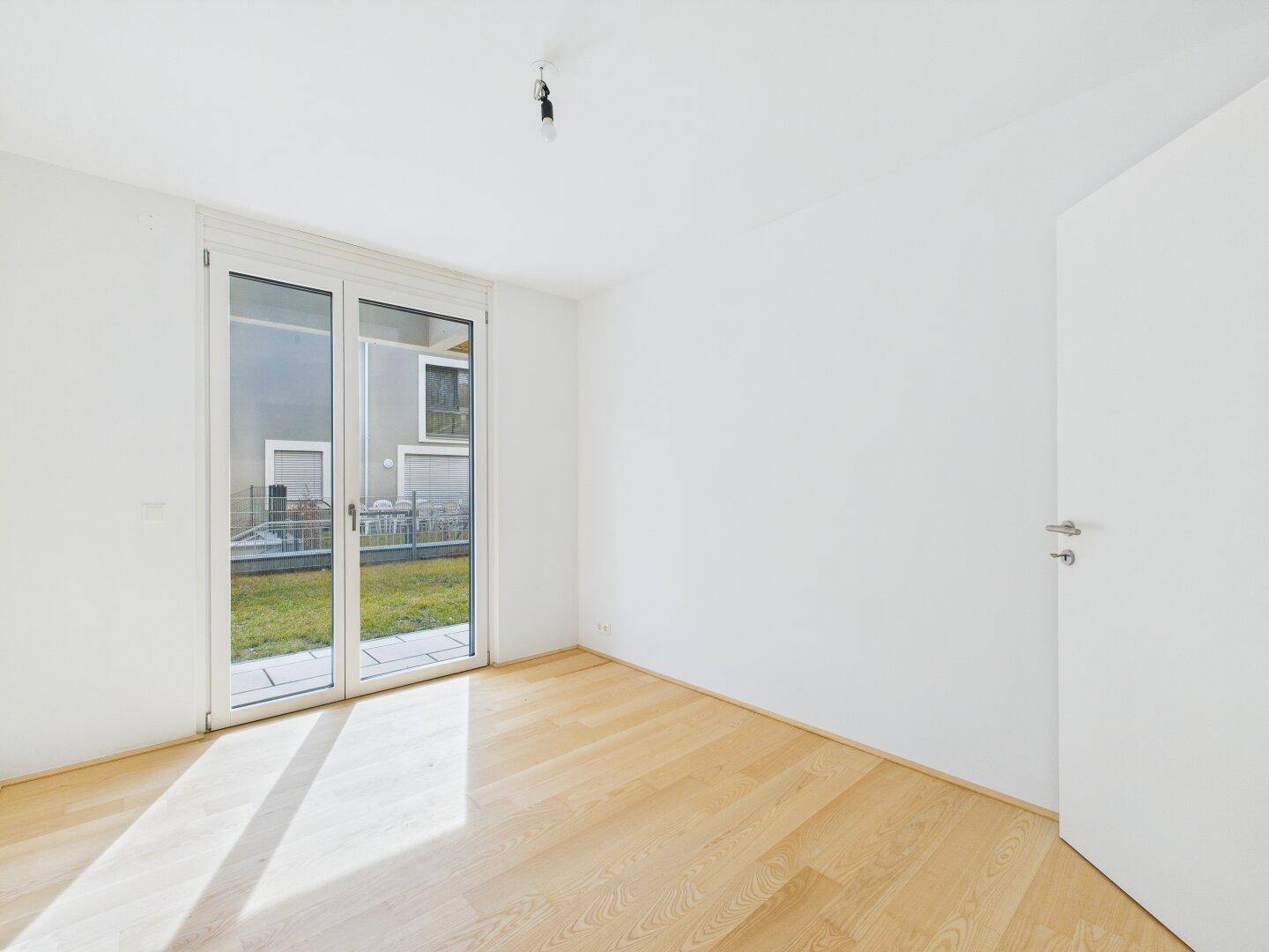 Helles Zimmer mit Parkettboden und Blick auf den Garten, ideal als Schlaf- oder Arbeitszimmer.