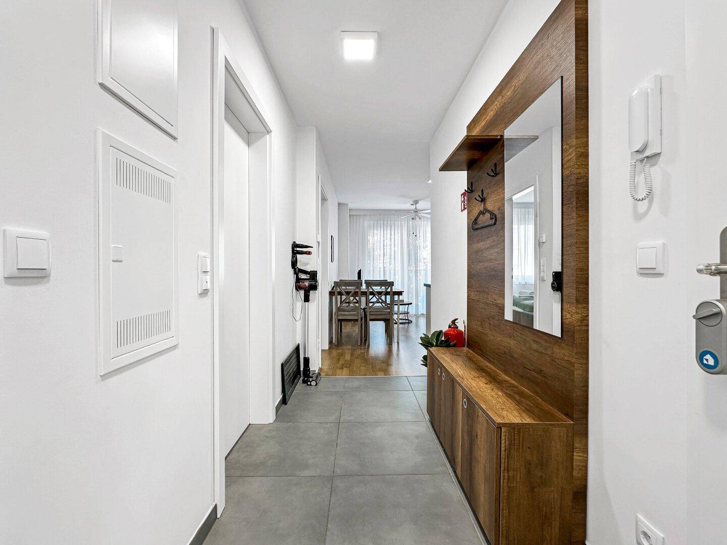 Heller Flur mit modernem Holzpaneel, Spiegel und Gegensprechanlage.