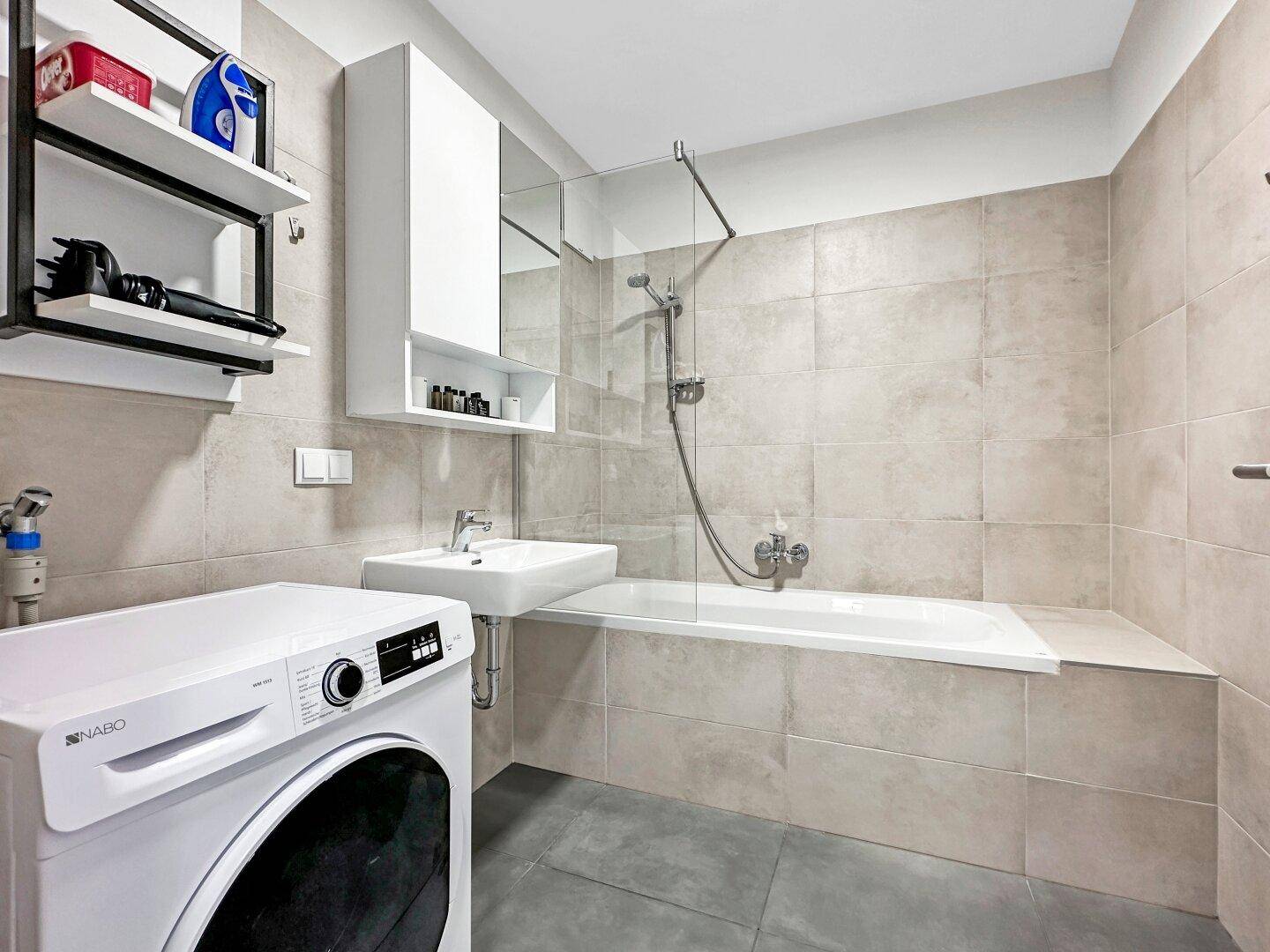 Modernes Badezimmer mit Badewanne, Waschbecken und Waschmaschine.
