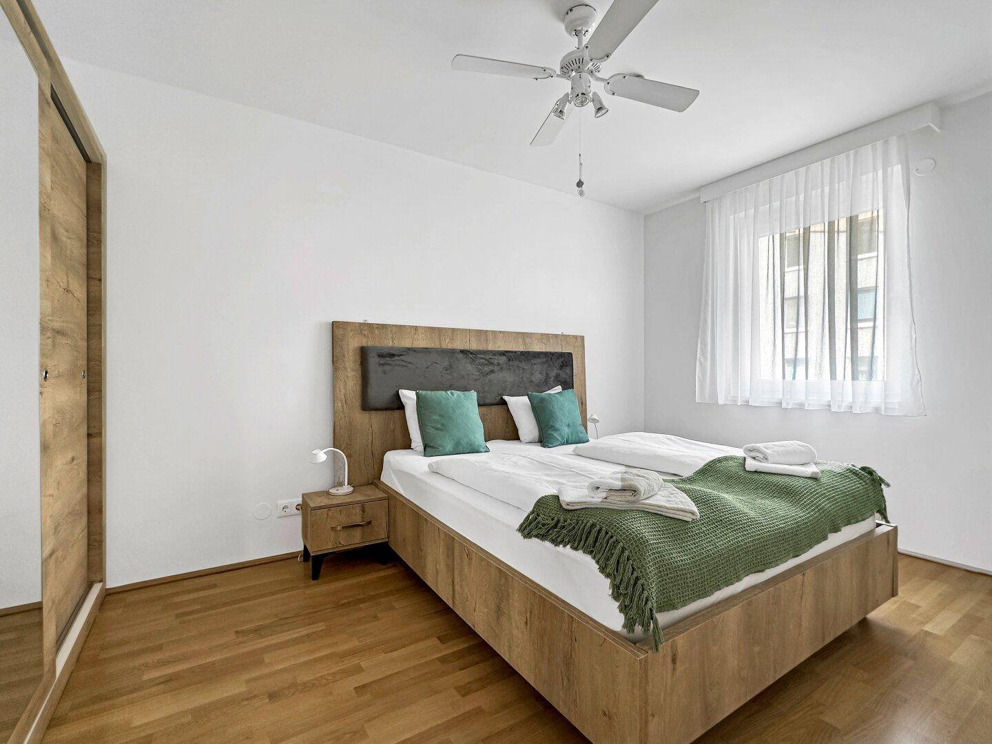 Gemütliches Schlafzimmer mit Doppelbett, Holzboden und Deckenventilator.