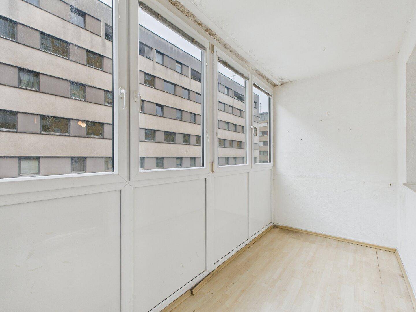 Verglaste Loggia mit Holzboden und Blick auf die umliegenden Gebäude.