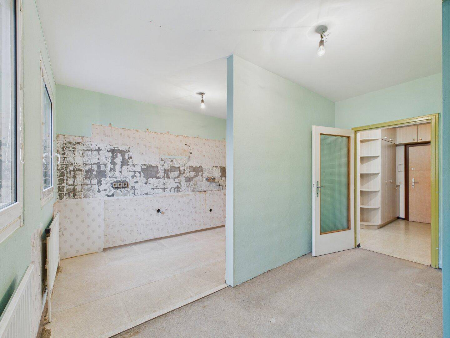 Küche in Renovierung mit hellgrünen Wänden und Blick auf den Flur mit Einbauschränken.