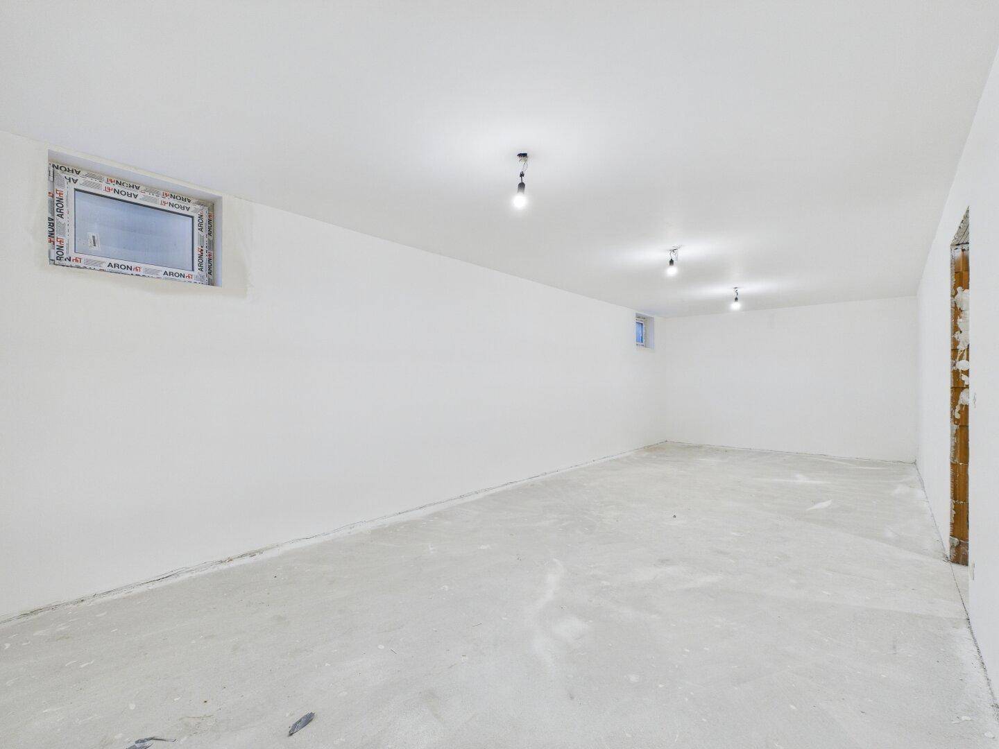Heller Kellerraum im Rohbau mit kleinen Fenstern und Betonboden, bereit für die Nutzung.