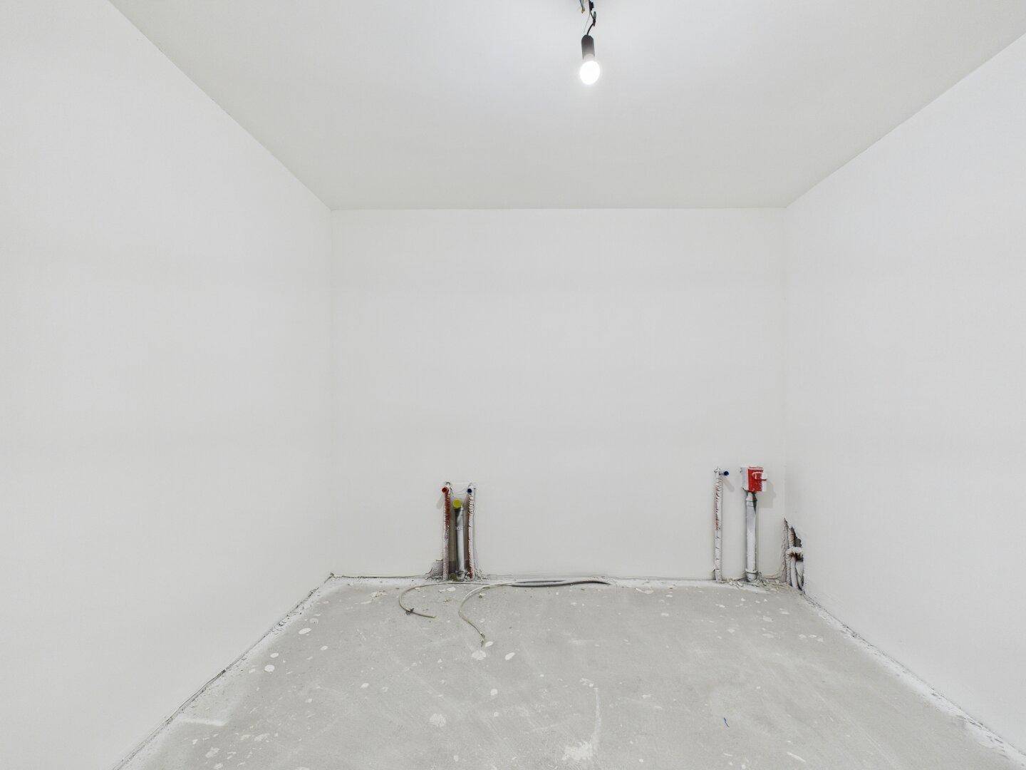 Kleiner Raum im Rohbau mit sichtbaren Leitungen für Installationen, ideal als Hauswirtschaftsraum.