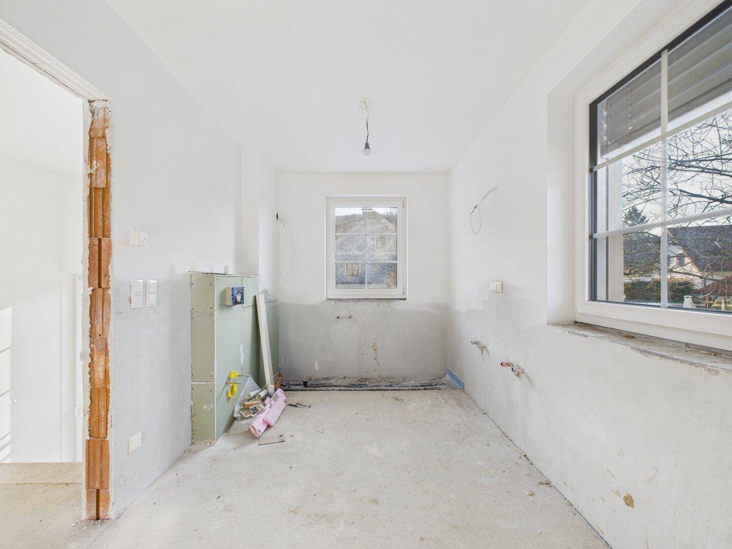 Unfertiger Raum mit sichtbaren Installationen, ideal für eine zukünftige Küche oder ein Badezimmer.