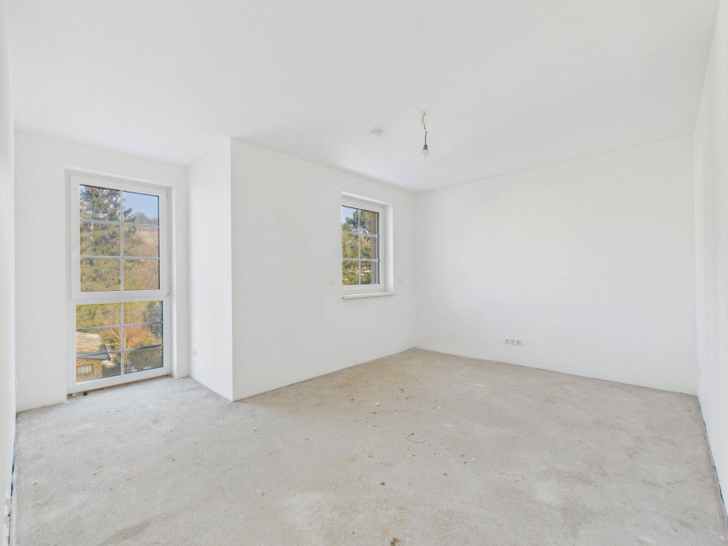 Unfertiges Zimmer mit großen Fenstern, die viel Licht hereinlassen und einen Ausblick bieten.