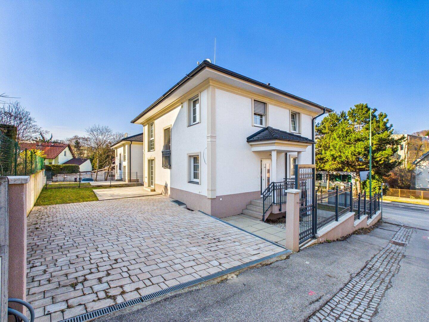 Ansicht des modernen Einfamilienhauses von der Straßenseite mit gepflasterter Auffahrt und einladendem Eingangsbereich.