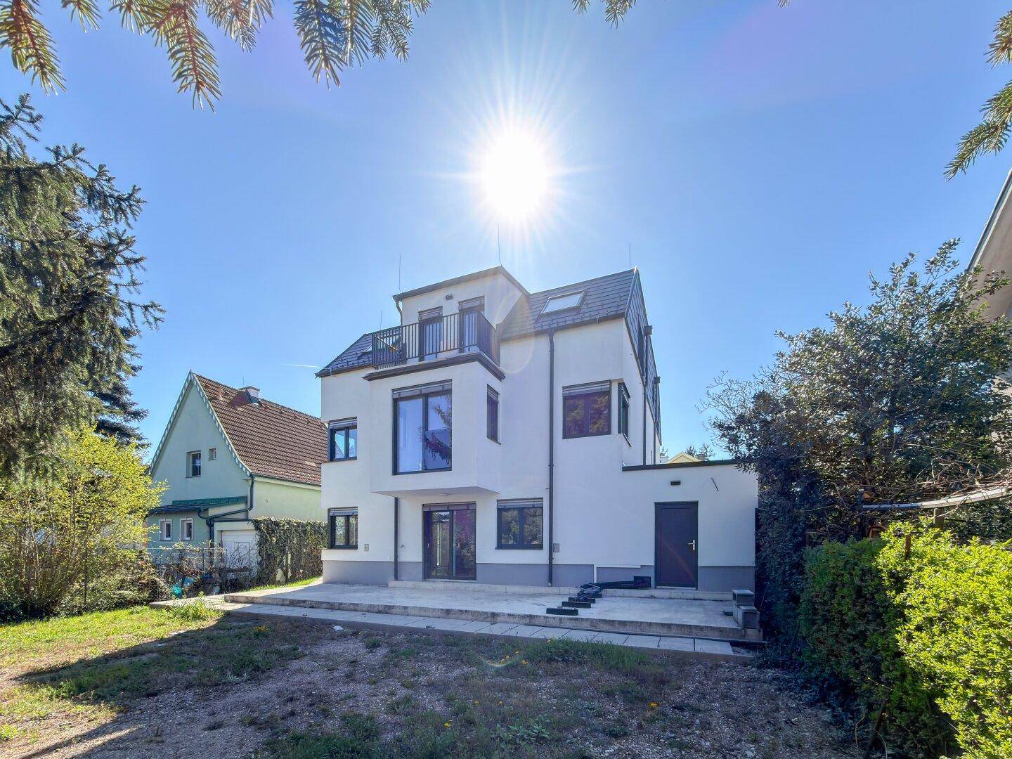 Sonnenverwöhntes Neubau-Haus mit moderner Architektur, Balkon und großzügiger Gartenfläche.