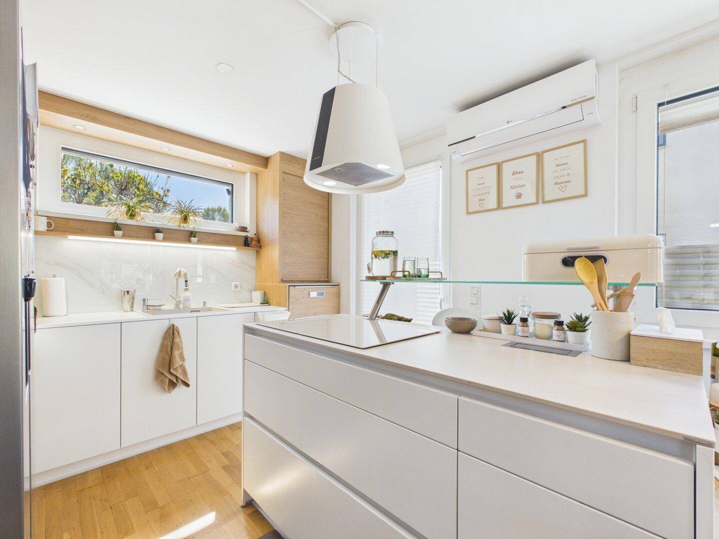 Moderne, helle Küche mit Kücheninsel, weißen Schränken und Holzdetails.