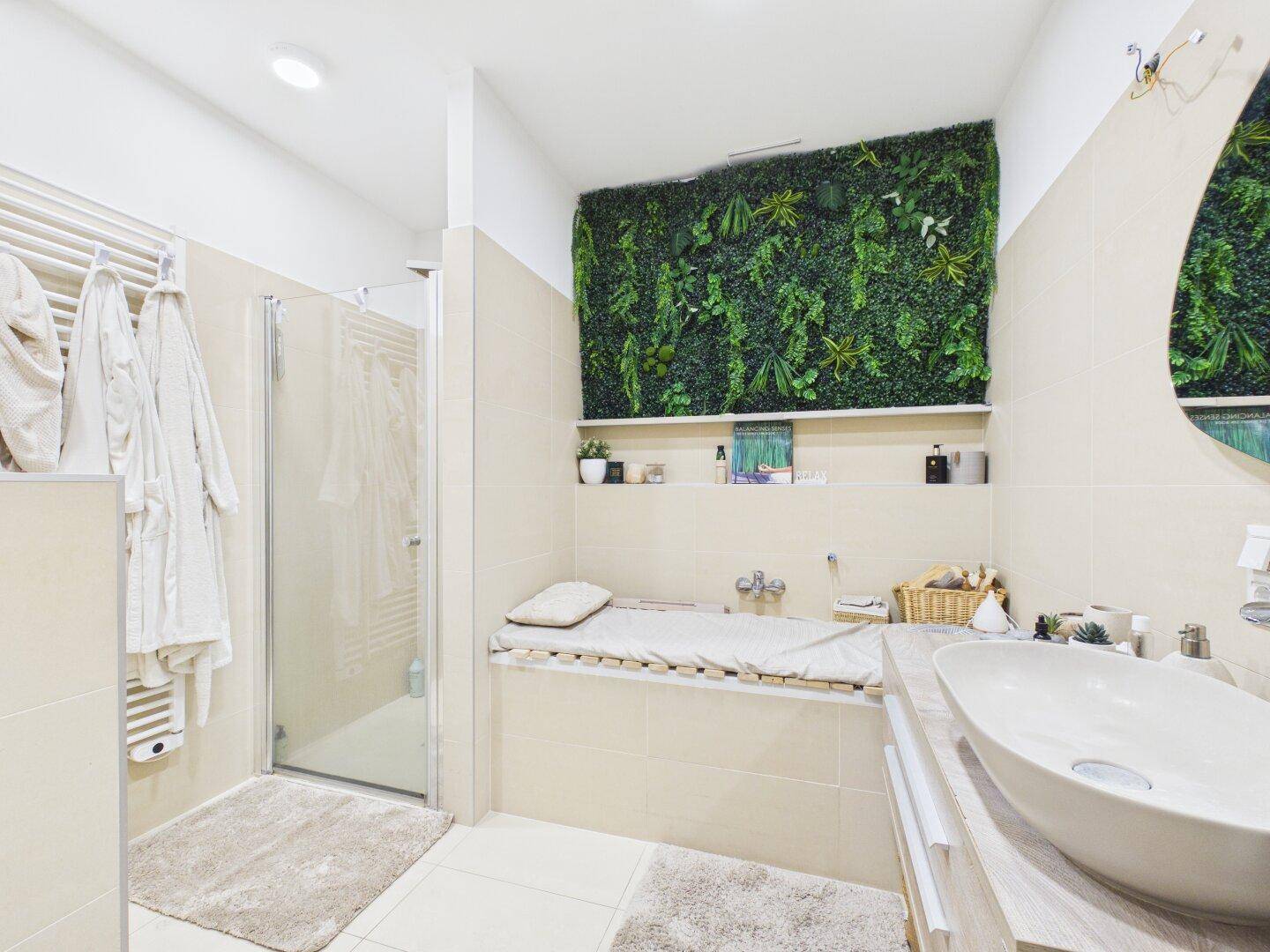 Modernes Badezimmer mit begehbarer Dusche, Waschbecken und grüner Pflanzenwand.