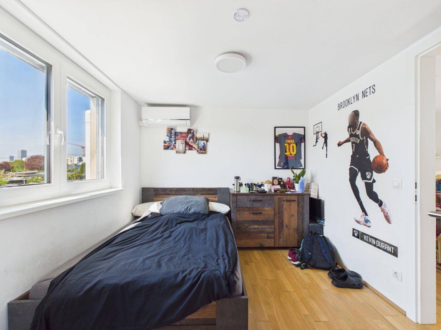 Jugendzimmer mit Einzelbett, Holzboden und sportlicher Wanddekoration.