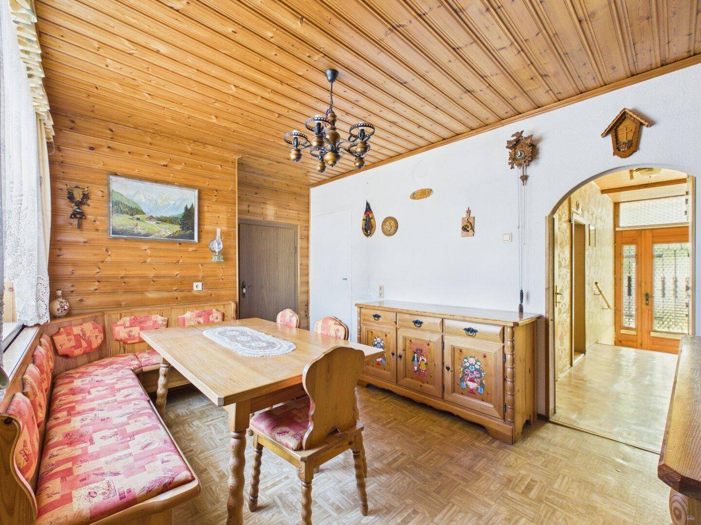 Traditionelles Esszimmer mit Holzvertäfelung, Holztisch, Eckbank und rustikalen Möbeln.