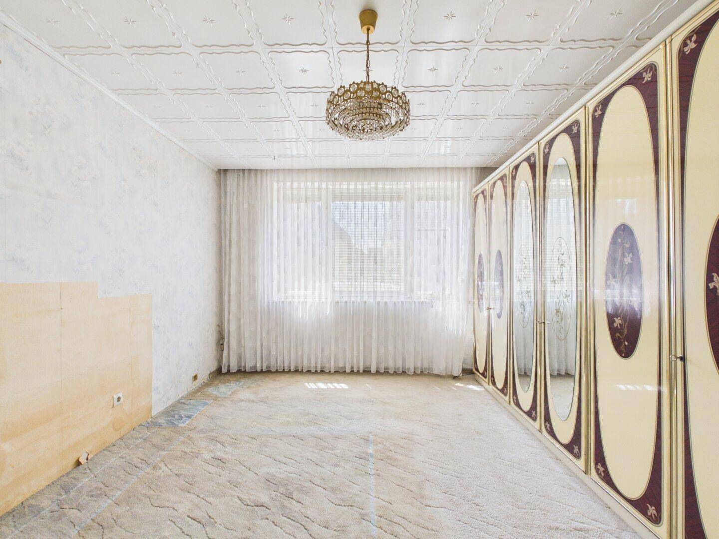 Schlafzimmer mit großem Spiegelschrank, dekorativer Decke und Fenster mit hellen Vorhängen.