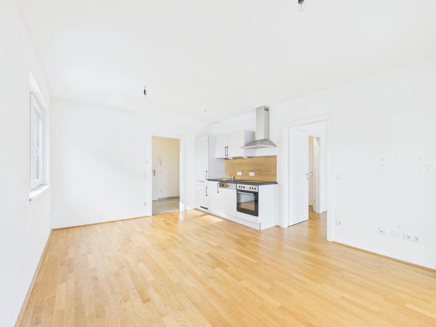 Geräumiger, heller Wohnbereich mit offener Küche und Holzboden, ideal für modernes Wohnen.