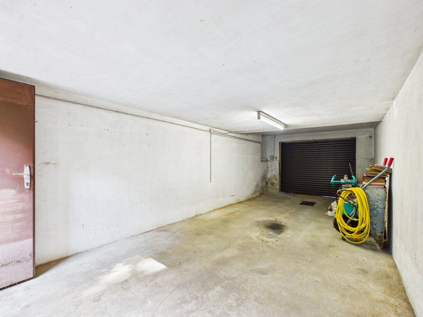 Geräumige Garage mit Betonboden und Rolltor, bietet Platz für ein Fahrzeug und Lagerung.