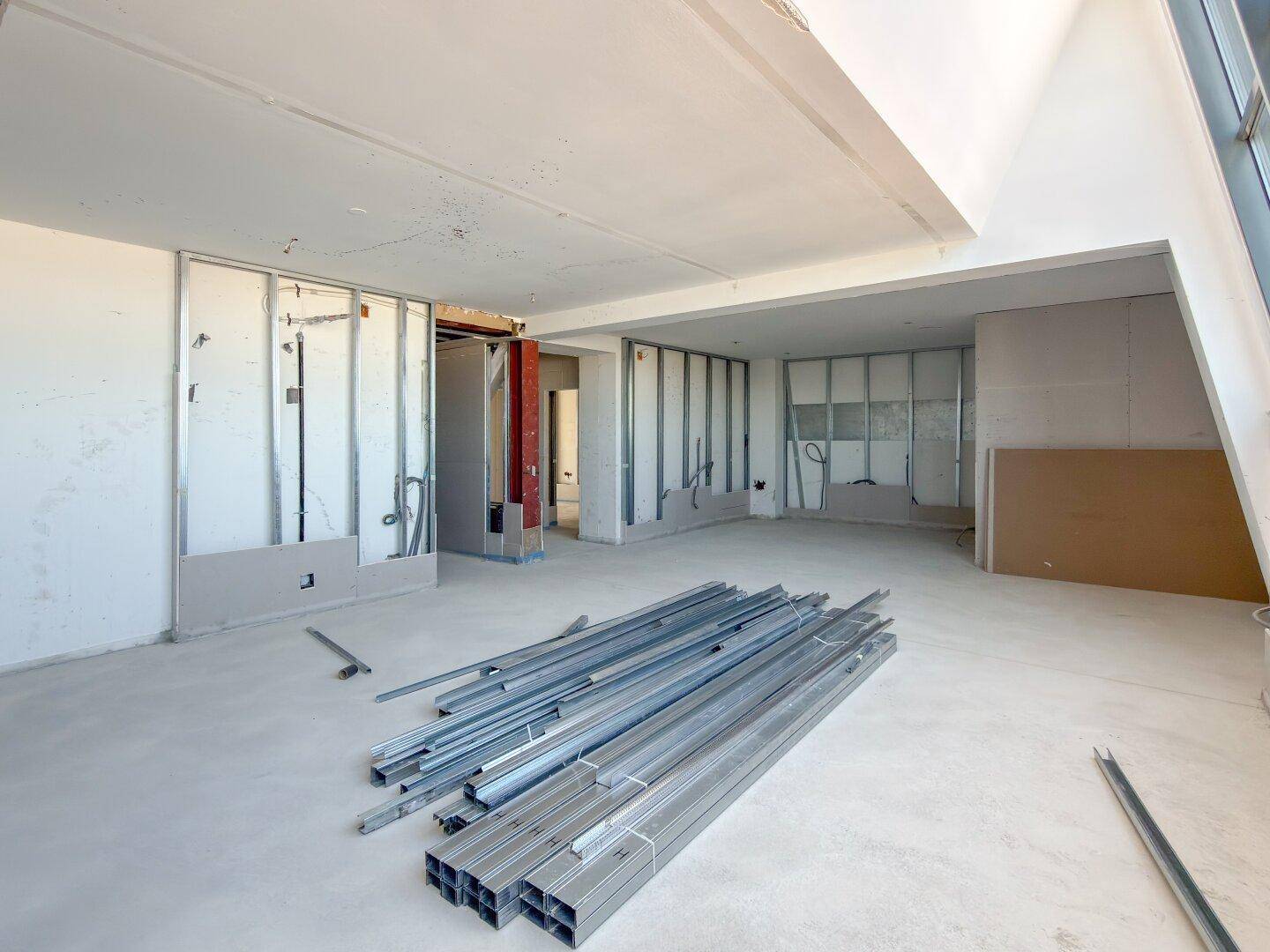 Baustelle eines Innenraums mit Trockenbauwänden und Rohinstallationen, bereit für den weiteren Ausbau.
