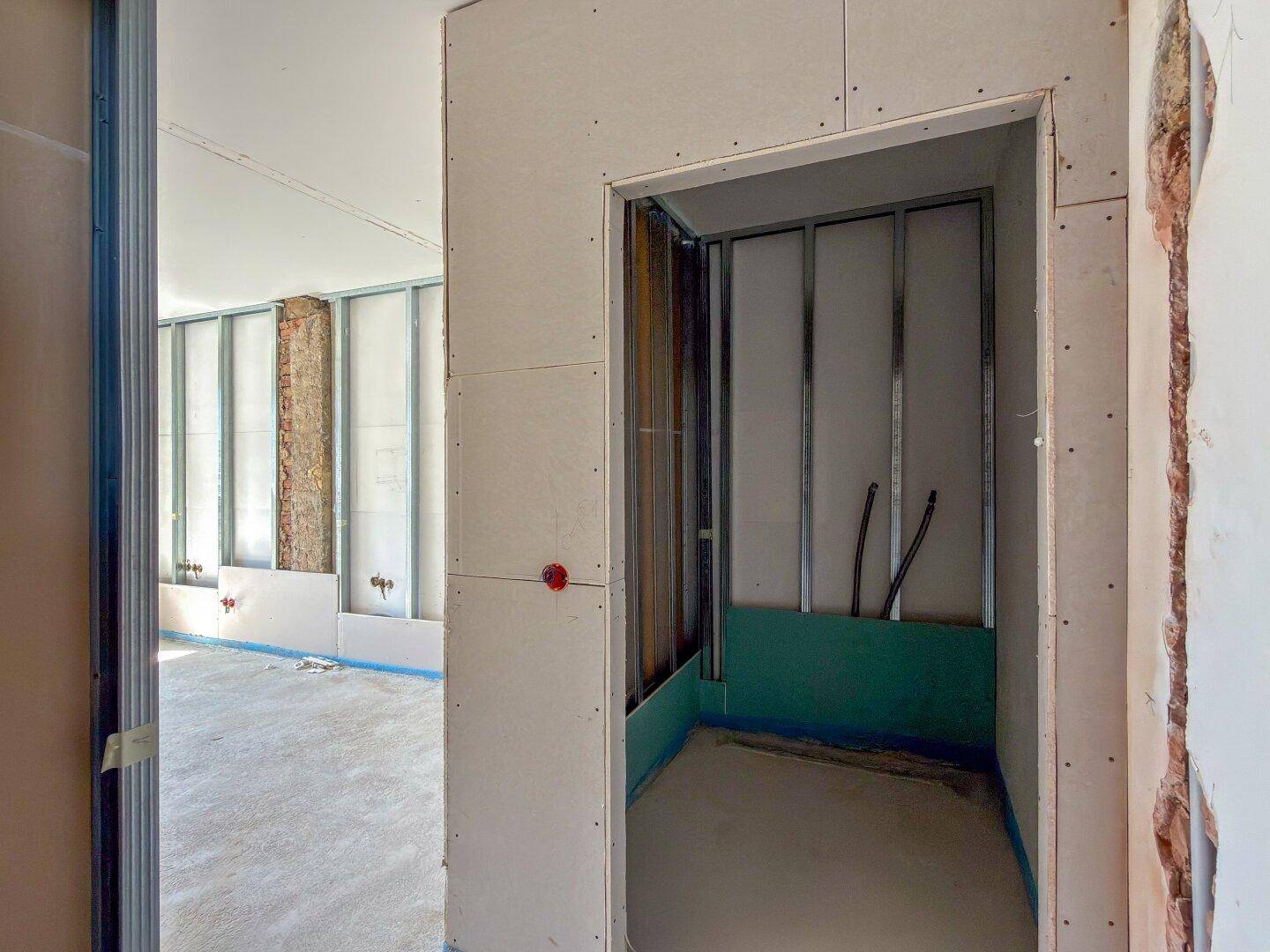 Rohbau eines kleinen Raumes oder einer Nische mit Trockenbauwänden und sichtbaren Installationen.