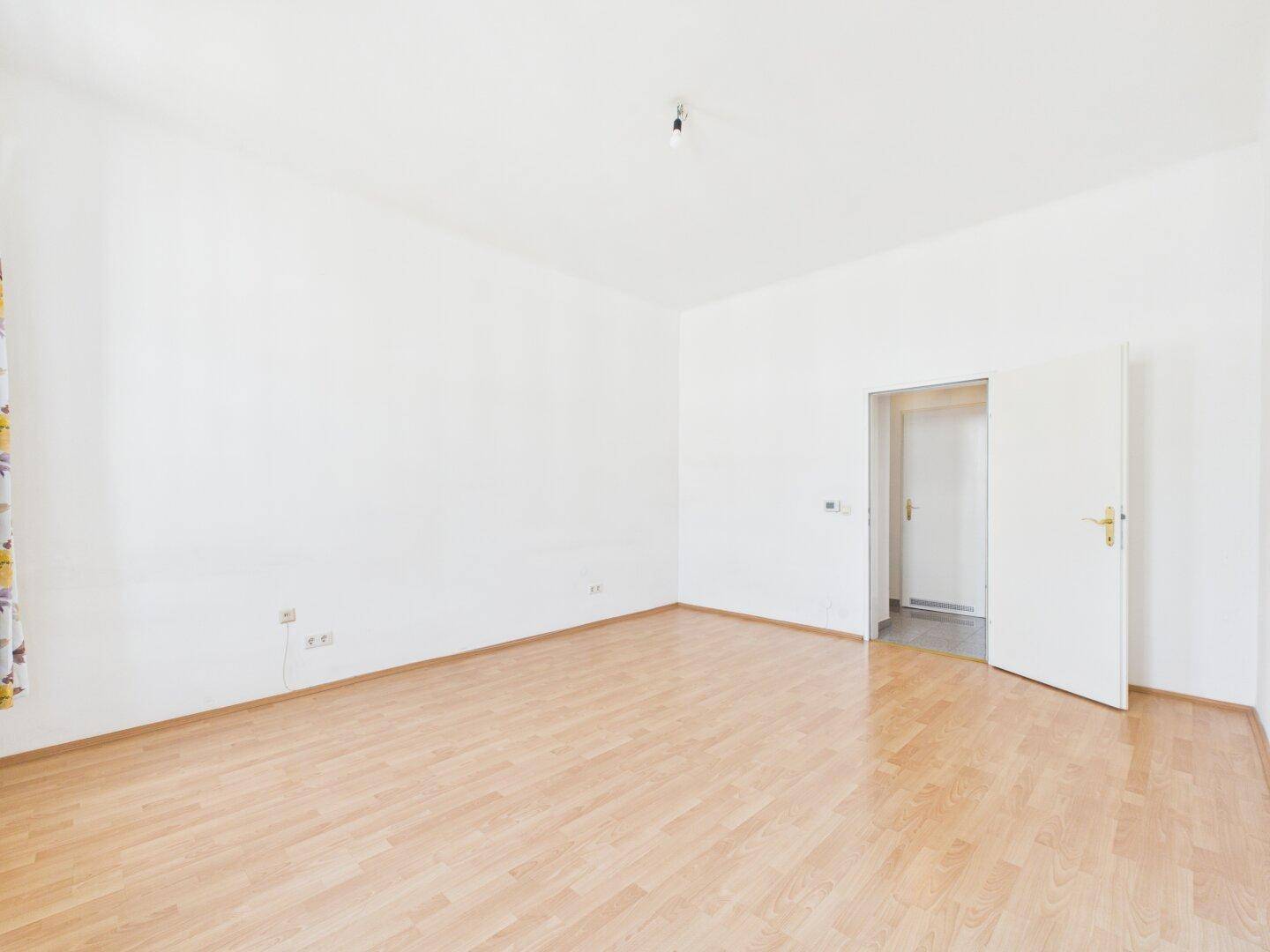 Geräumiges, unmöbliertes Zimmer mit Laminatboden und Zugang zu einem weiteren Raum.