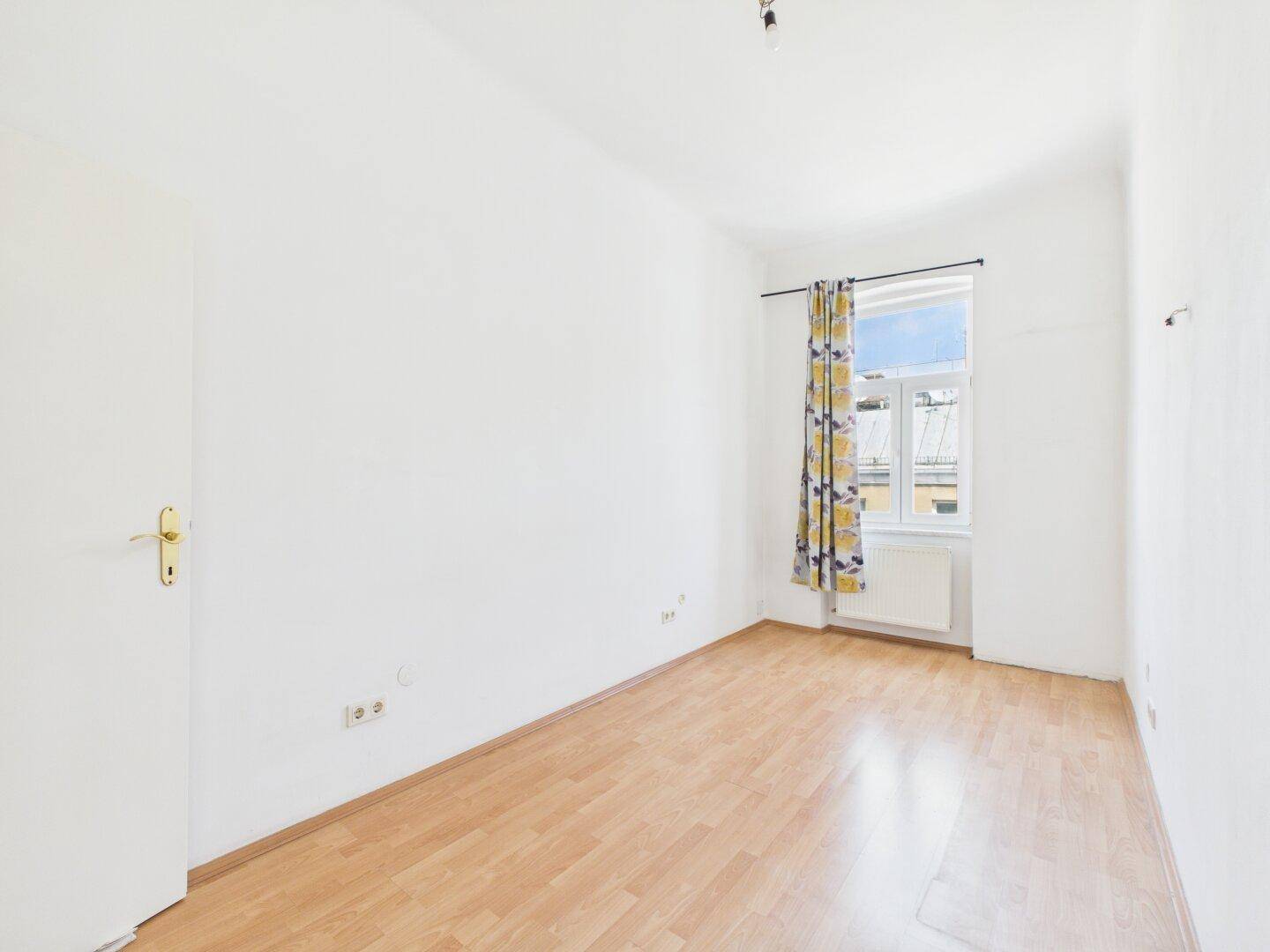 Kleineres, helles Zimmer mit Laminatboden und einem Fenster, ideal als Schlaf- oder Arbeitszimmer.