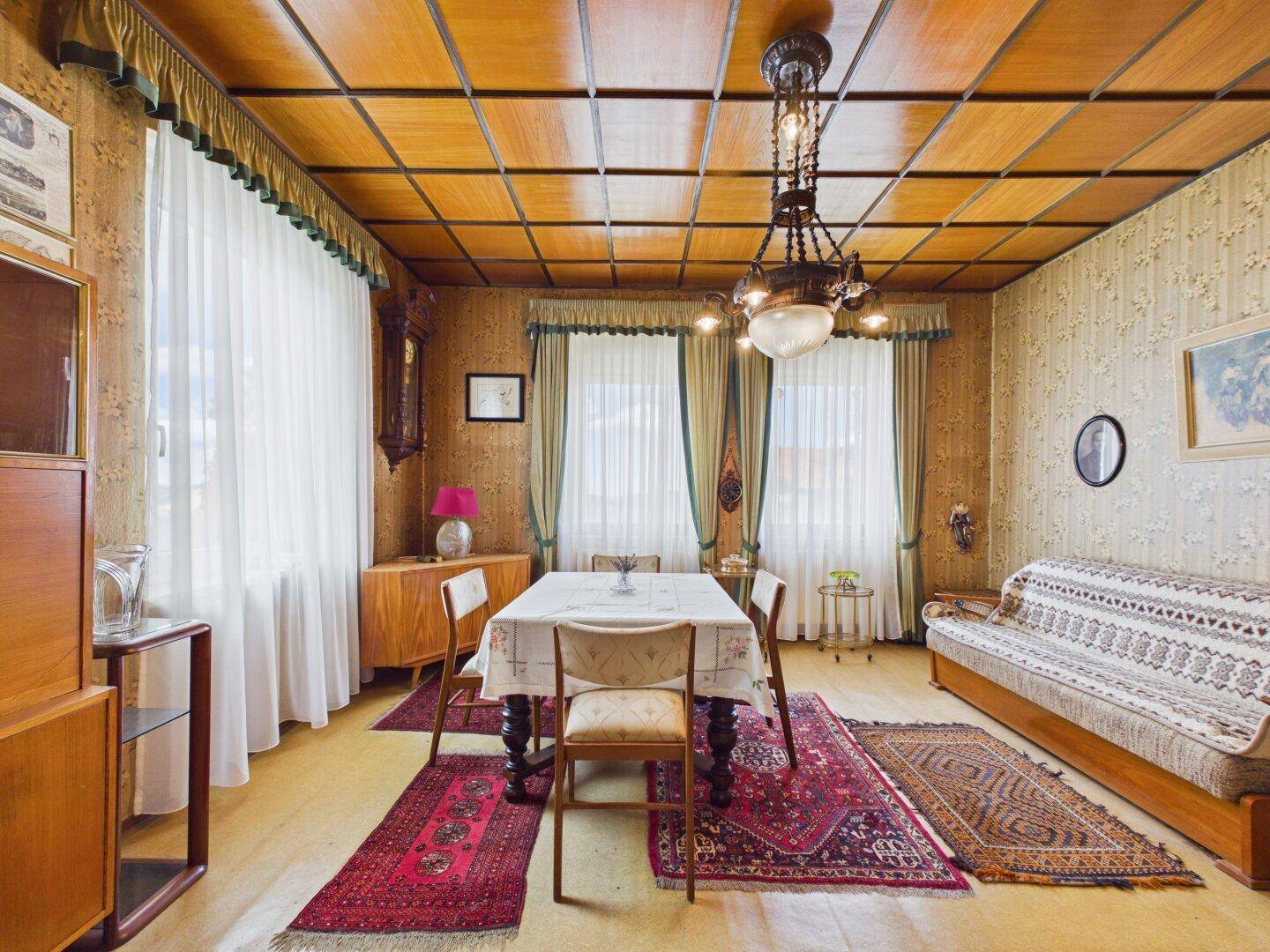 Gemütlicher Wohn- und Essbereich mit Holzdecke, Teppichen und traditionellen Möbeln.