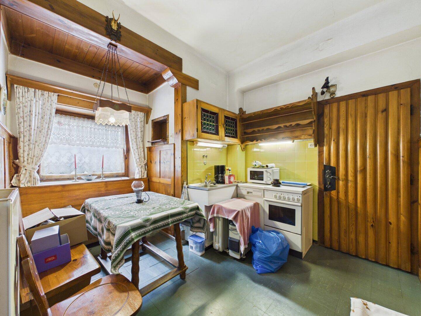 Einfache Küche im Landhausstil mit Holztisch, gelben Fliesen und rustikalen Holzelementen.