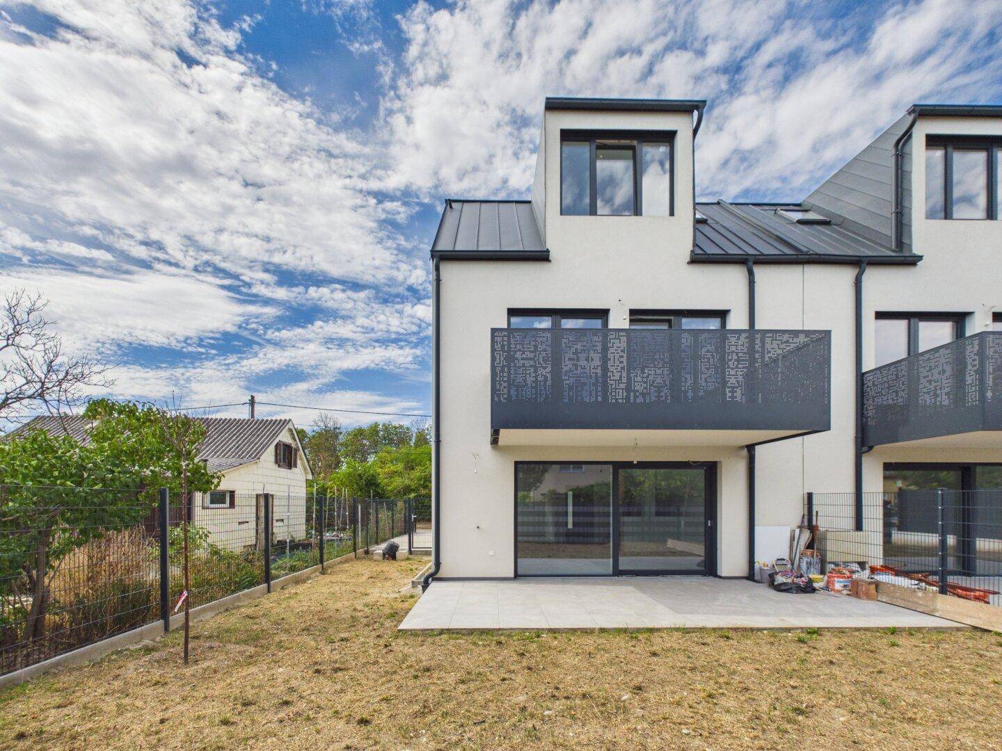 Rückseite der Reihenhäuser mit Terrasse, Gartenbereich und modernem Balkon.