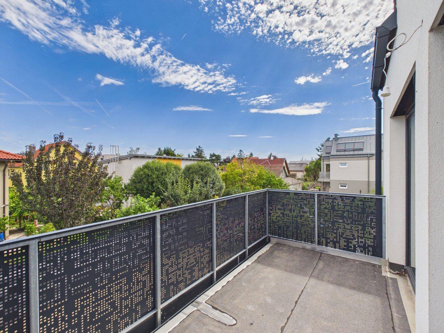 Moderner Balkon mit perforiertem Geländer und Blick auf die Umgebung.