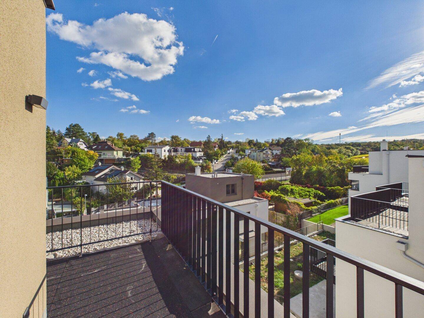 Balkon mit schwarzem Geländer und Panoramablick über die grüne Umgebung und die Stadt.