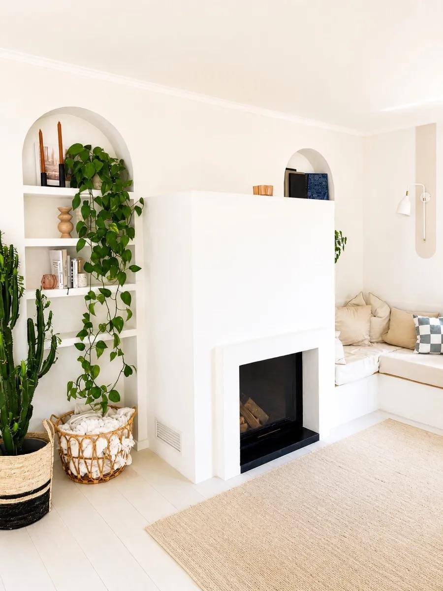 Helles Wohnzimmer mit Kamin, integrierten Regalen und gemütlicher Sitzecke.
