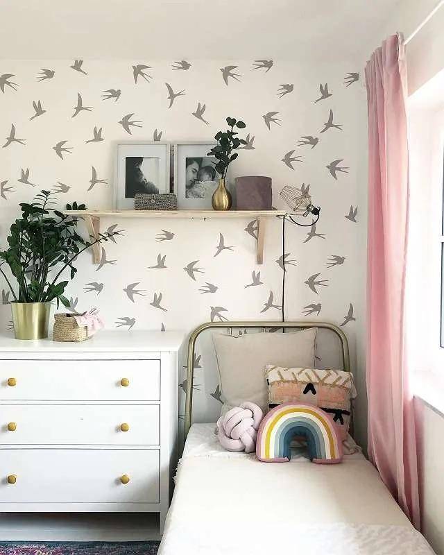 Kinderzimmer mit verspielter Tapete, Einzelbett und weißer Kommode.