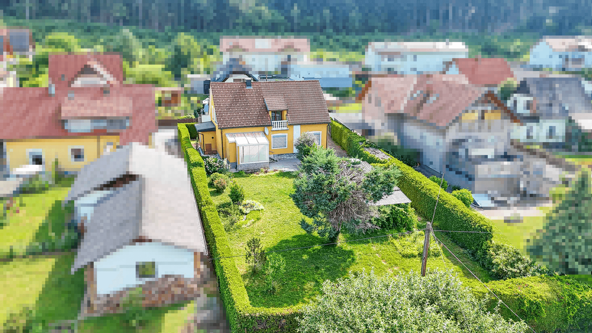Vogelperspektive des Hauses mit großem, gepflegtem Garten, umgeben von einer hohen Hecke.