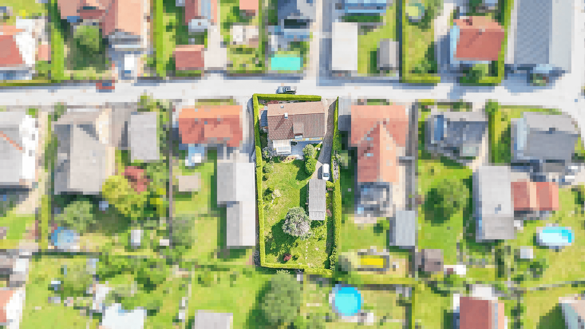Draufsicht des Grundstücks mit Haus, Garten und umliegender Wohnbebauung in einer grünen Umgebung.