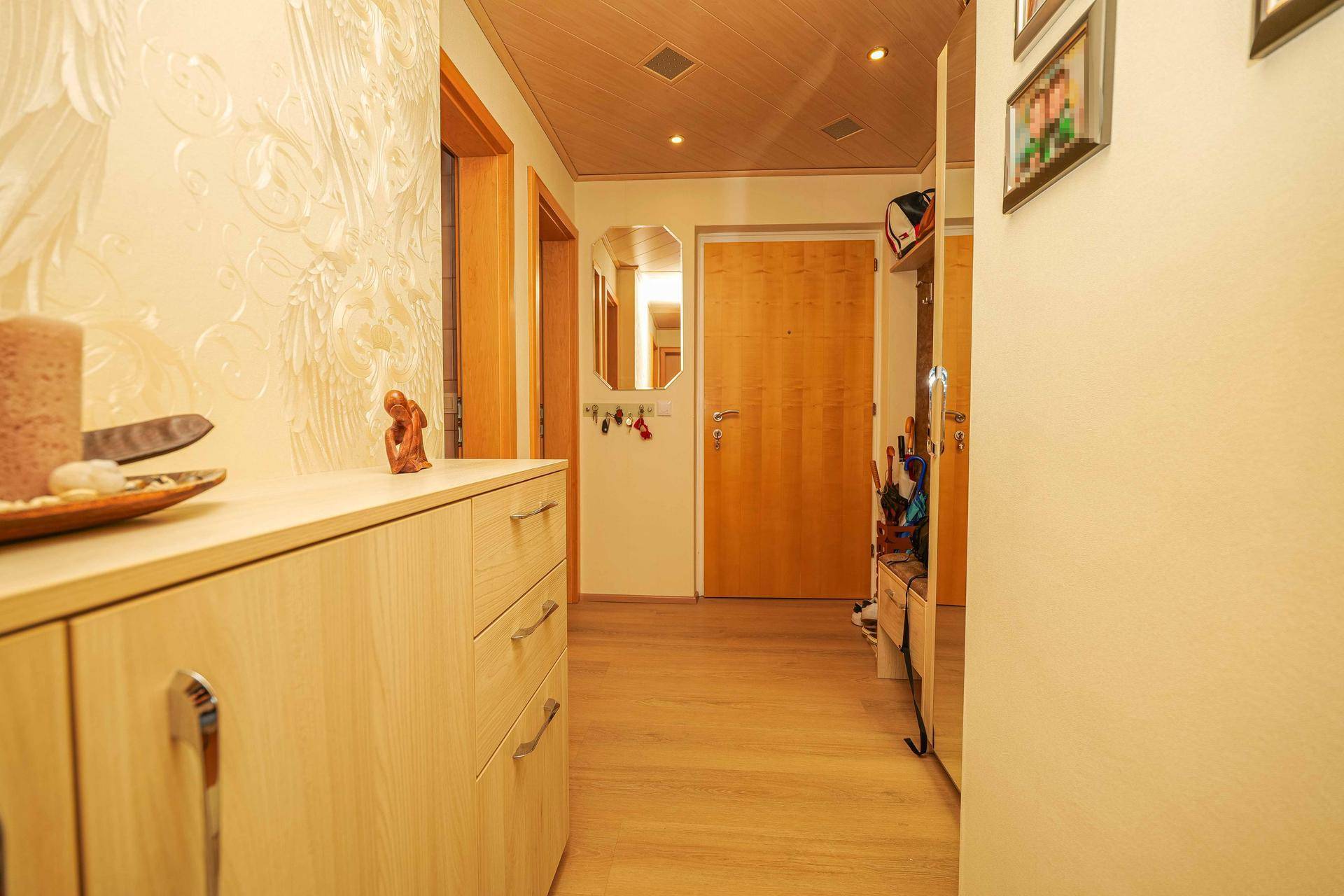 Heller Eingangsbereich mit Holzmöbeln, Spiegelschrank und warmem Holzboden.