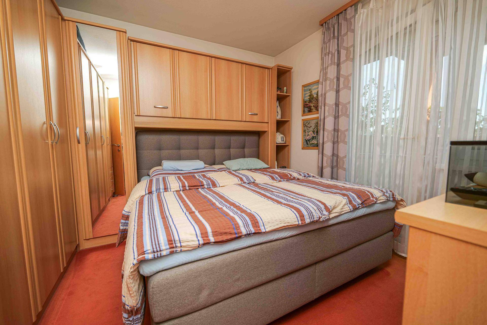 Schlafzimmer mit Doppelbett, praktischen Einbauschränken und Teppichboden.