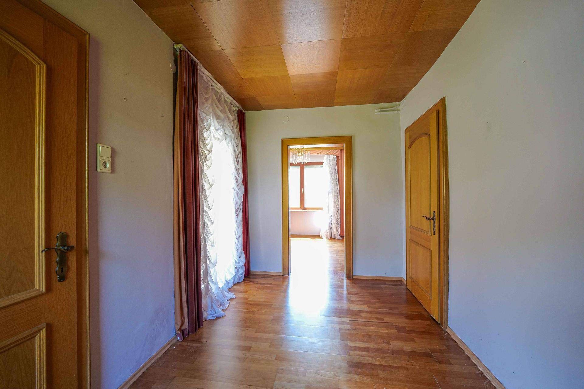 Heller Flur mit Holzboden und Holztüren, der zu weiteren Räumen mit viel Tageslicht führt.