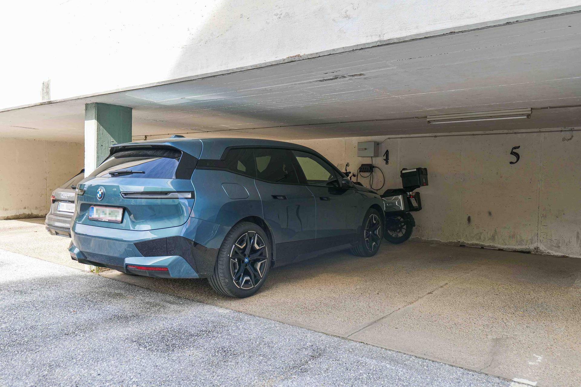 Überdachter Stellplatz in der Tiefgarage mit einem Elektrofahrzeug und Ladestation.