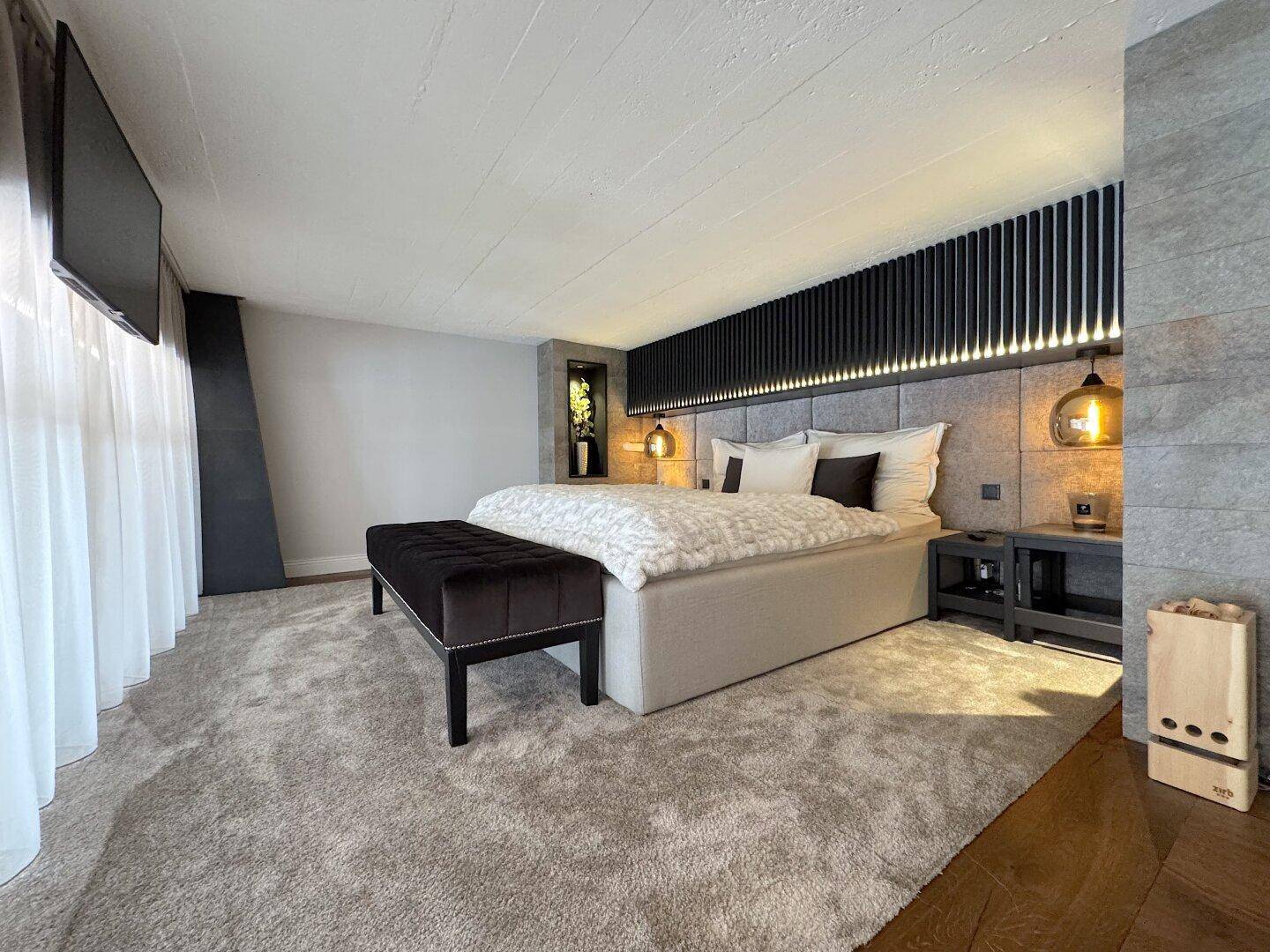 Elegantes Schlafzimmer mit großem Bett, Teppichboden und moderner Wandgestaltung.