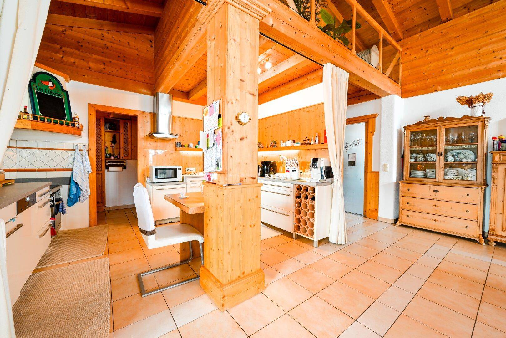 Rustikale Küche mit Holzelementen, Fliesenboden, integrierten Geräten und Weinregal.