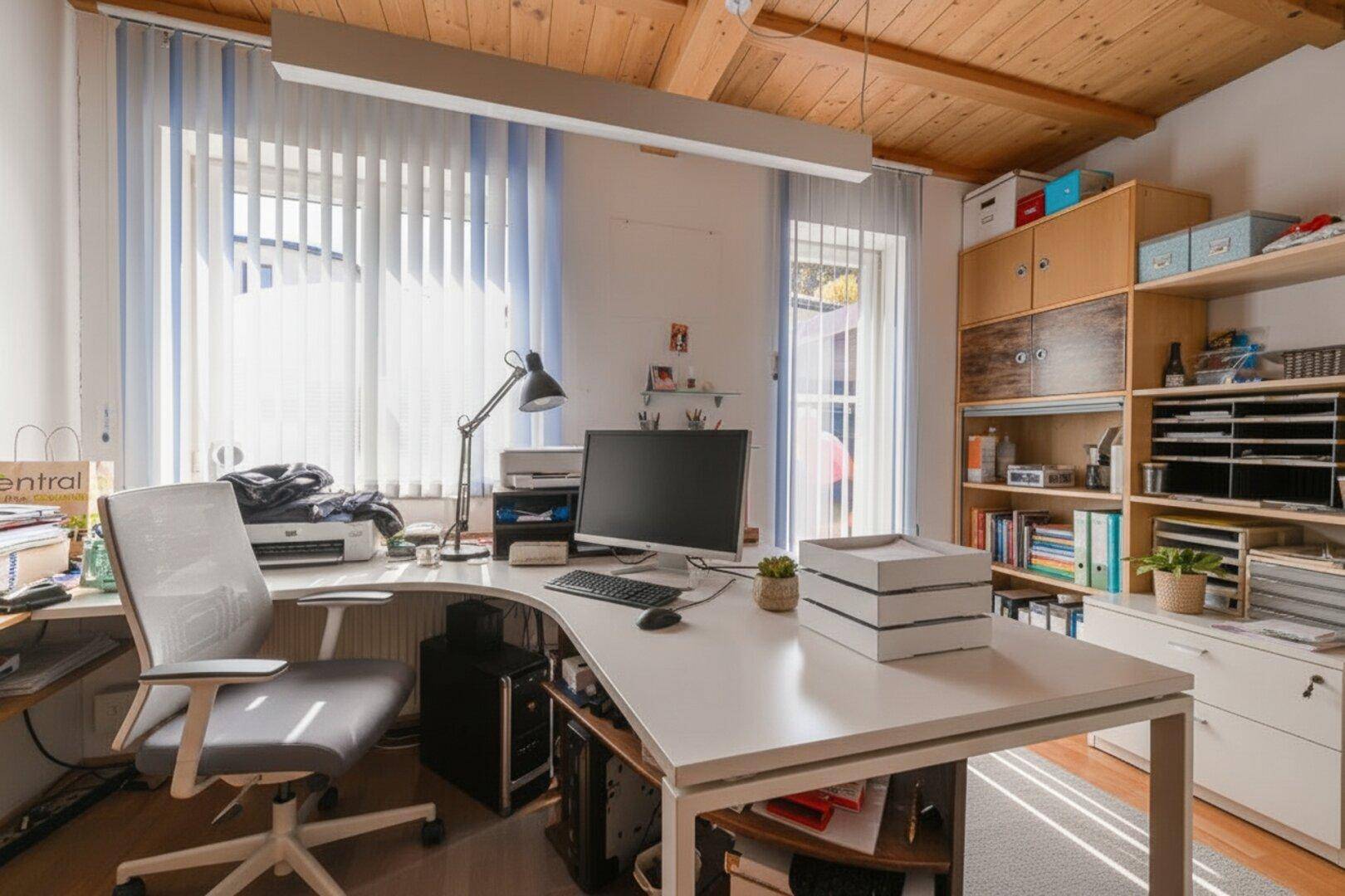 Geräumiges Arbeitszimmer mit großem Schreibtisch, Regalen und viel Tageslicht.