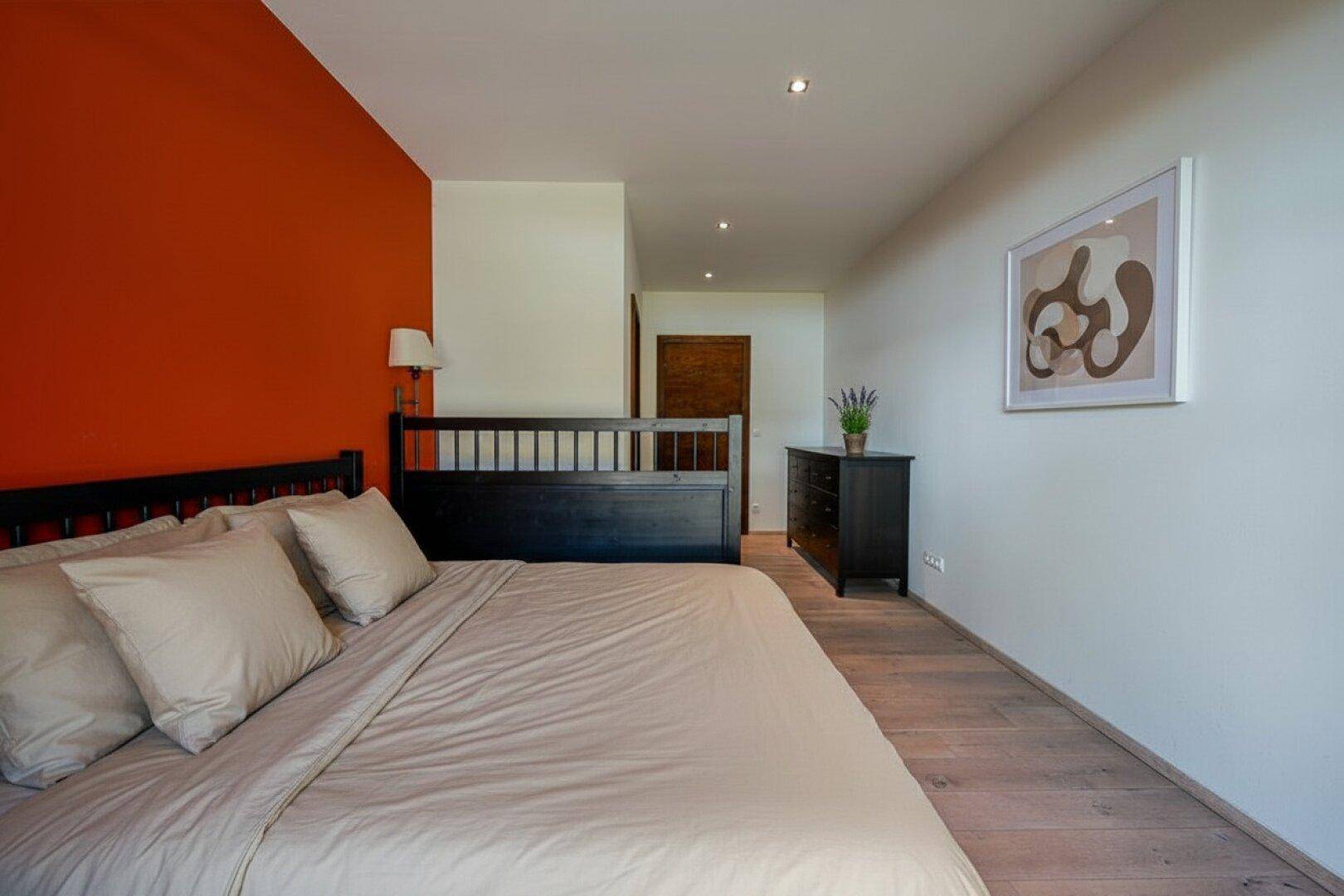 Schlafzimmer mit Akzentwand in Terrakotta, Holzboden und schlichtem, modernem Design.