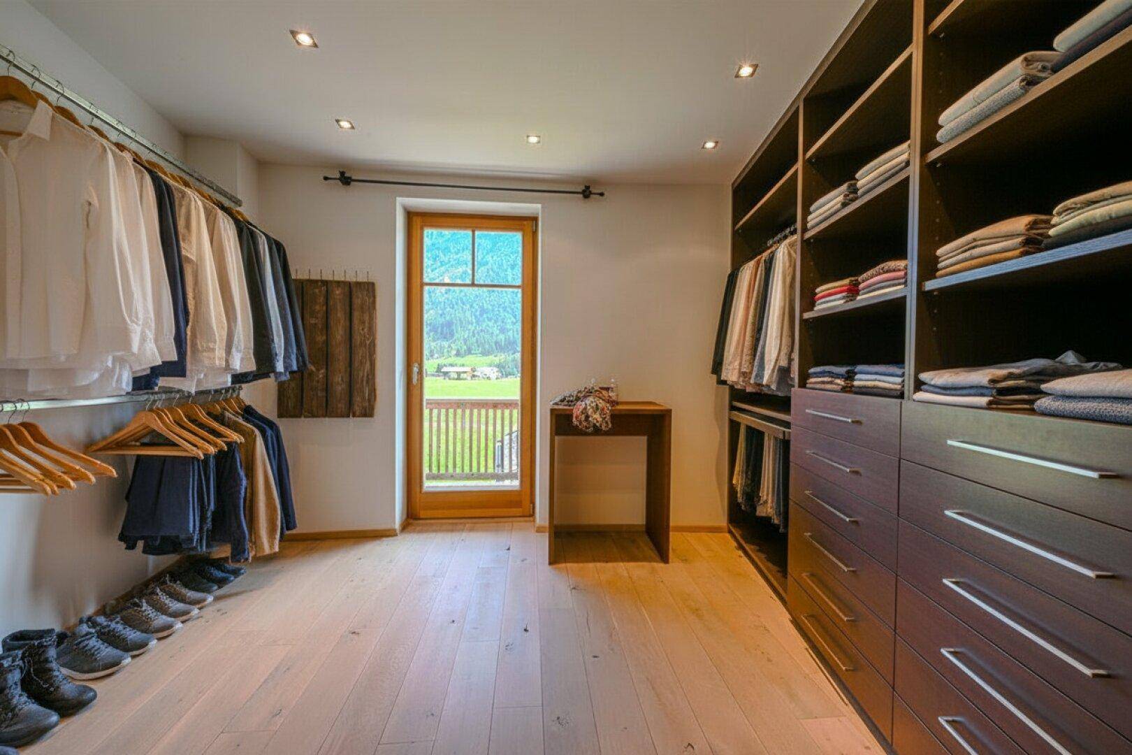 Geräumiger begehbarer Kleiderschrank mit viel Stauraum und einem Fenster mit Bergblick.