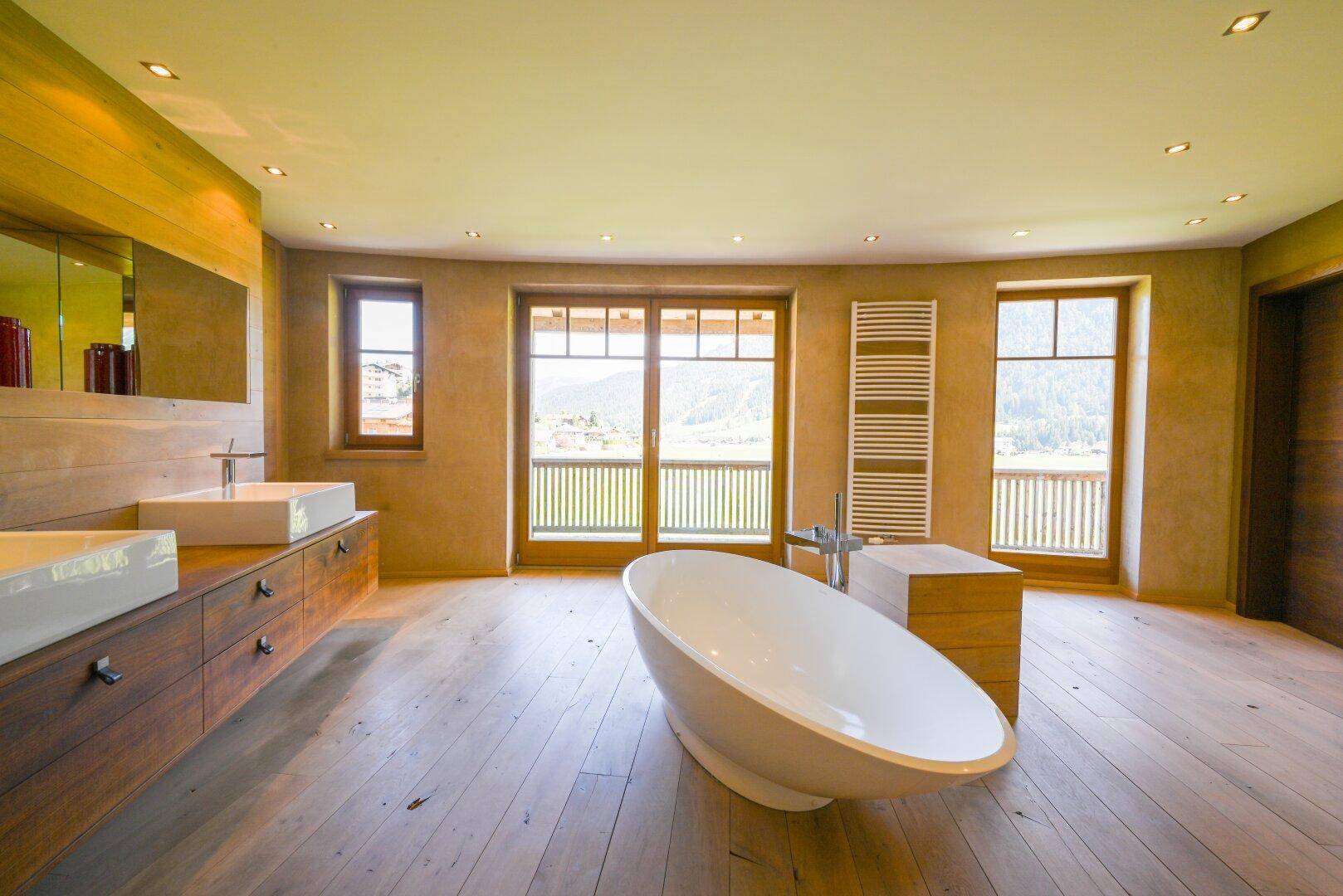 Modernes Badezimmer mit freistehender Badewanne, zwei Waschbecken und Bergblick.