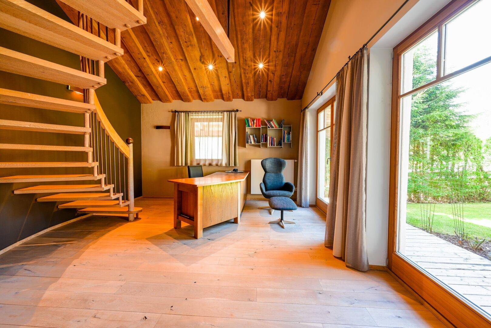 Helles Arbeitszimmer mit Holzdecke, Wendeltreppe und großen Fenstern zum Garten.