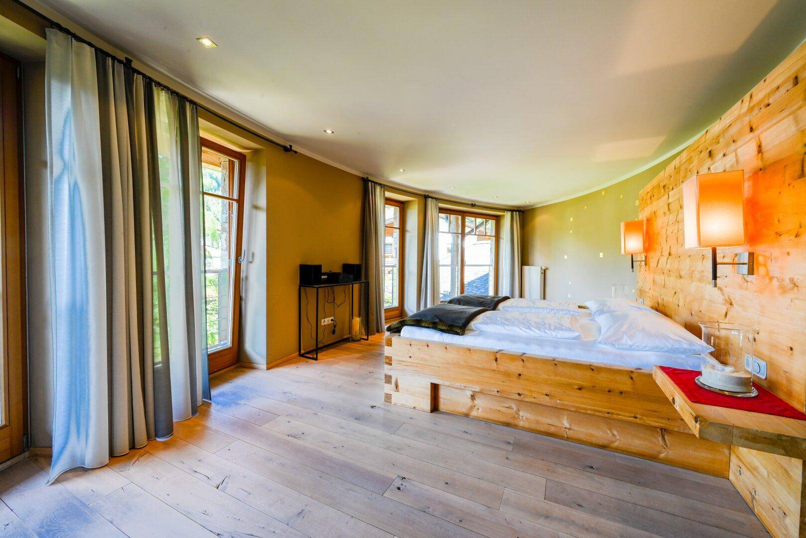 Gemütliches Schlafzimmer mit Holzwänden, Doppelbett und Zugang zu einem Balkon.