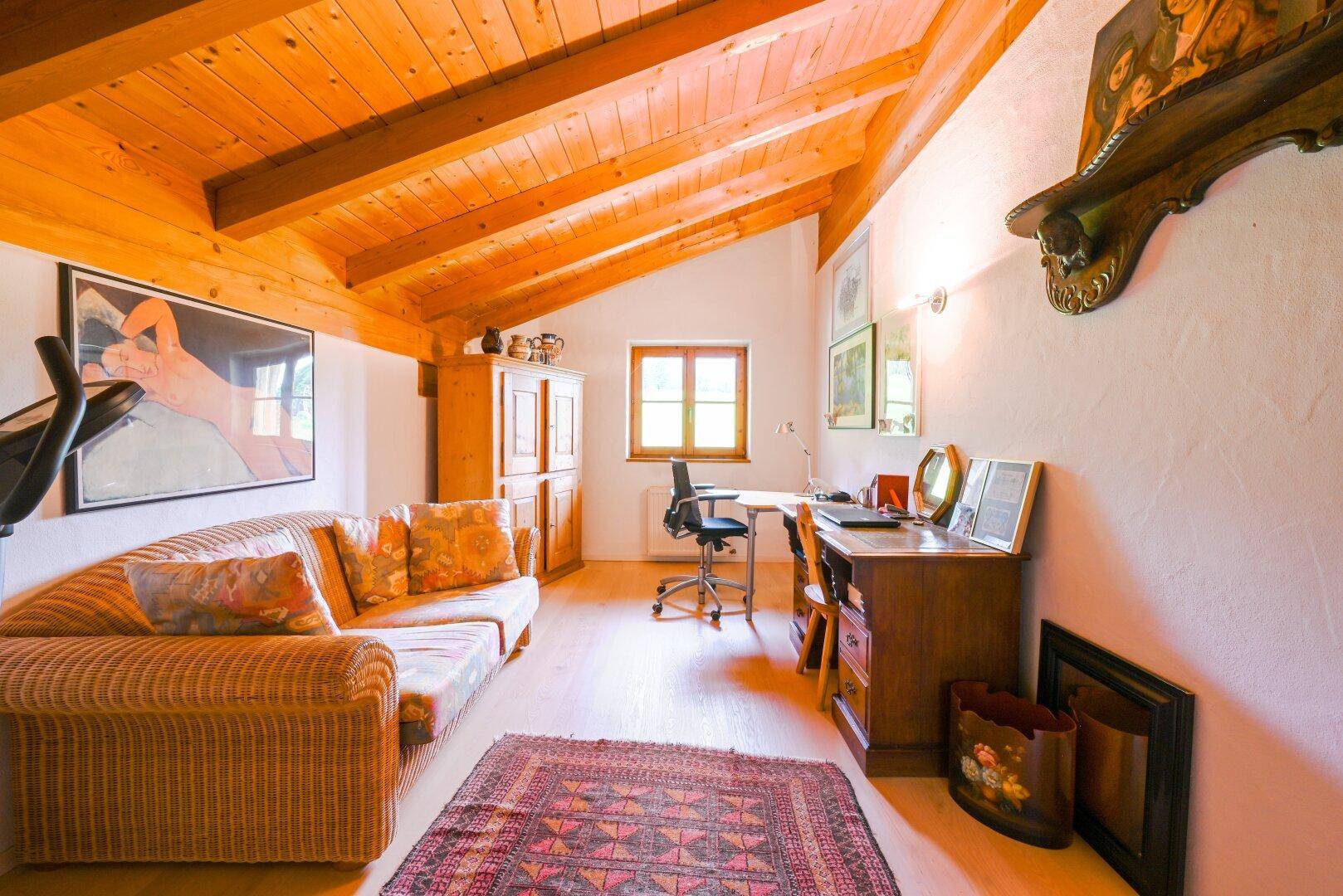 Helles Arbeitszimmer im Dachgeschoss mit Holzbalkendecke, Holzboden und Blick ins Grüne.