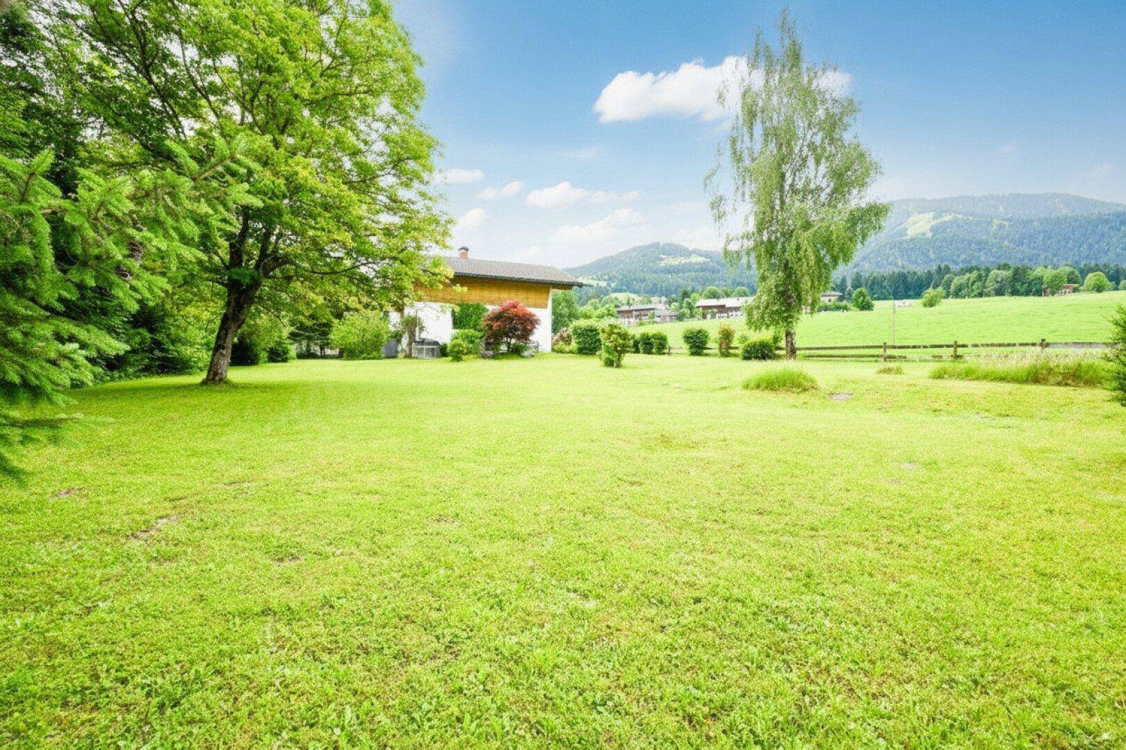 Weitläufiger Garten mit Rasenfläche und Panoramablick auf die umliegende Berglandschaft.