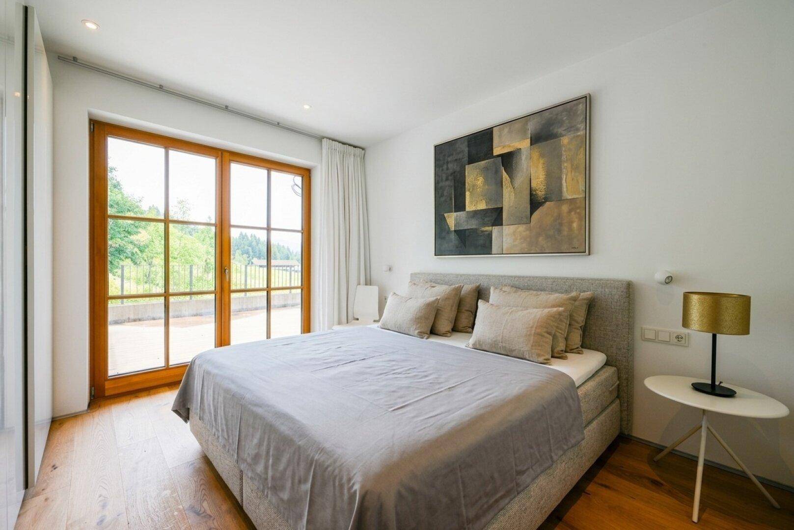 Komfortables Schlafzimmer mit Doppelbett, Holzboden und Zugang zu einem Außenbereich.