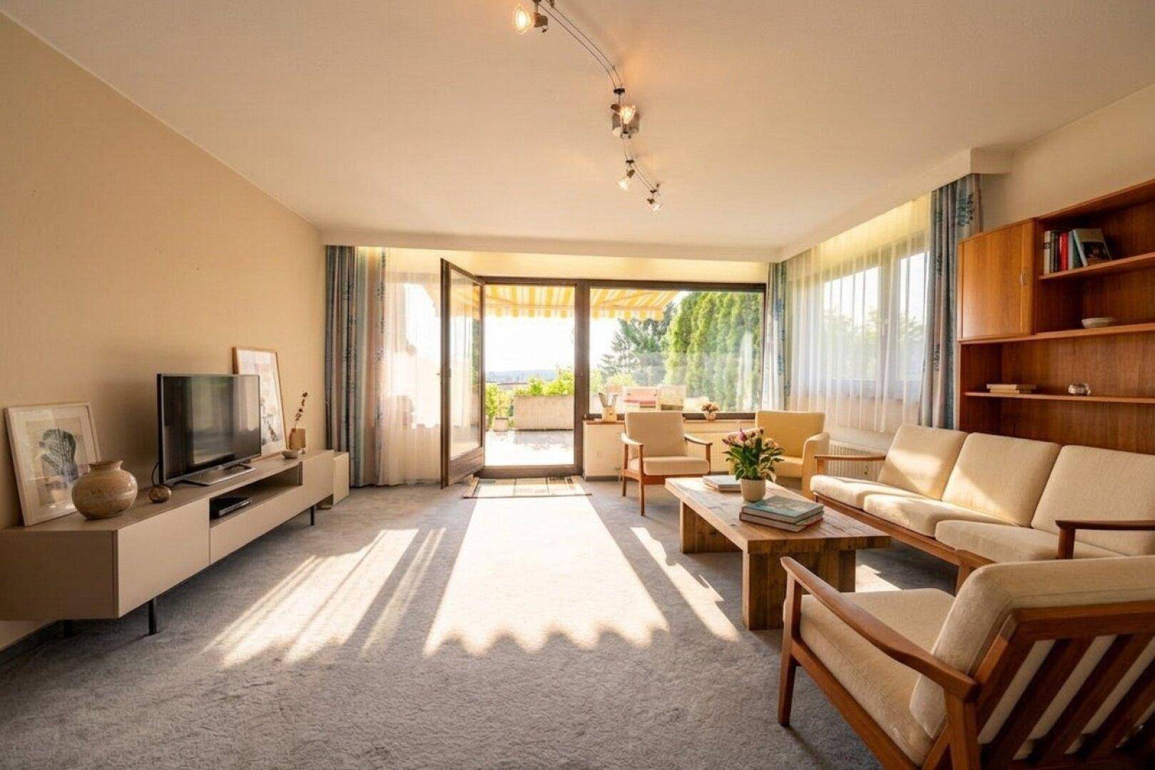 Geräumiges Wohnzimmer mit Teppichboden, viel Tageslicht und direktem Zugang zur Terrasse.