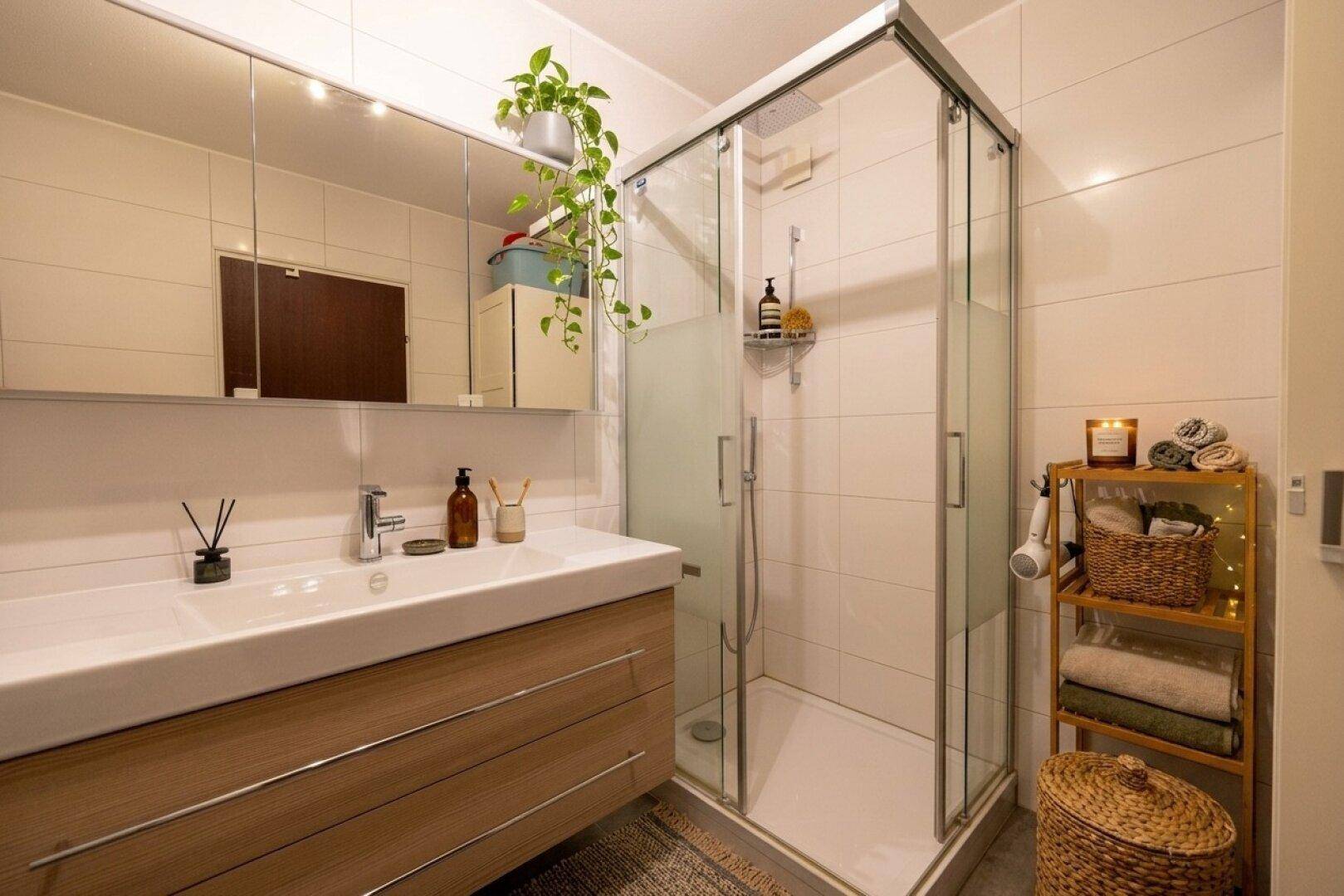 Helles Badezimmer mit Duschkabine, modernem Waschtisch und Spiegelschrank.