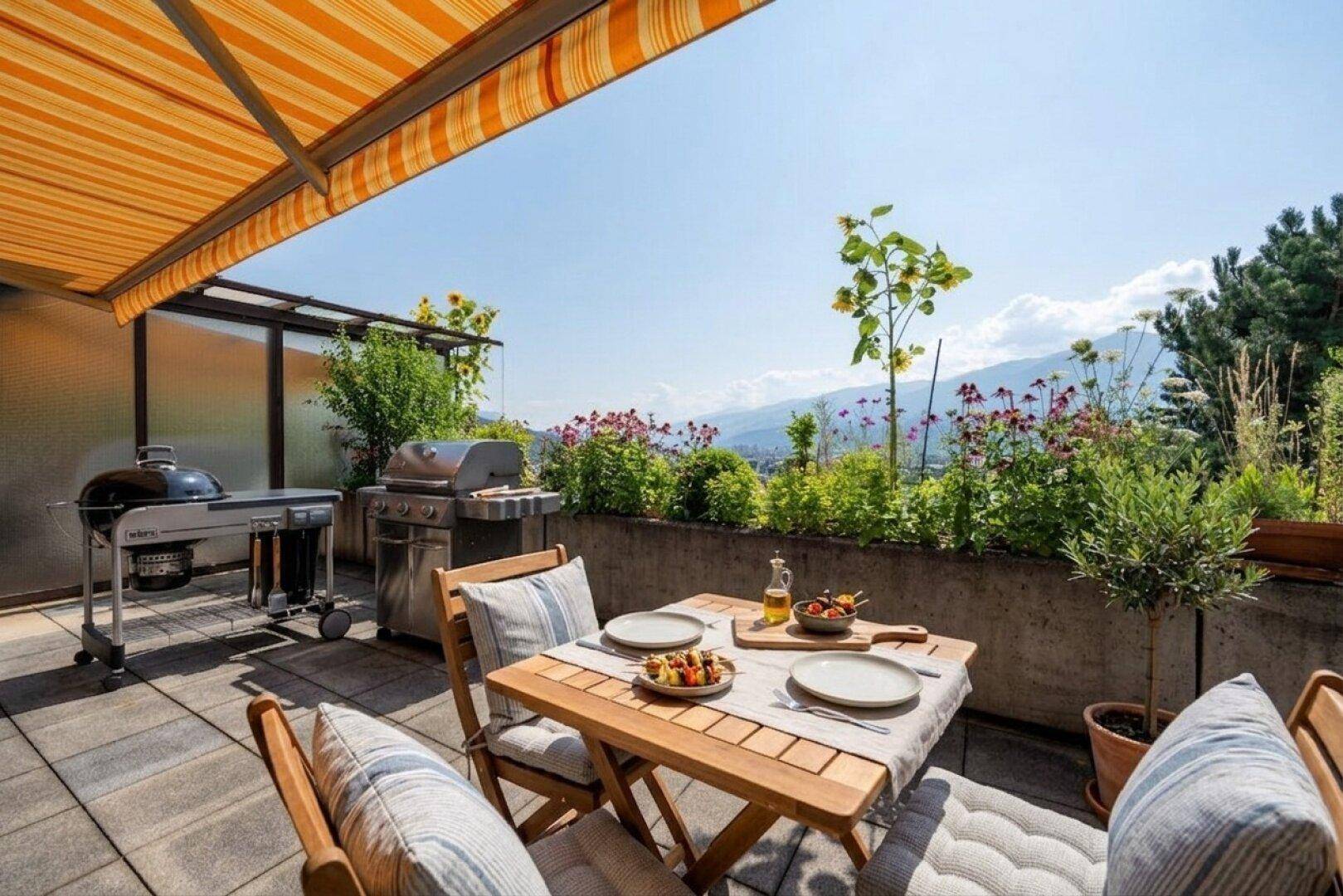Sonniger Essbereich auf der Terrasse mit Grillstation und weitem Blick auf die Berge.